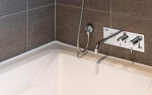 a bath tub with a faucet in a bathroom at The Line Hotel in Yangpyeong