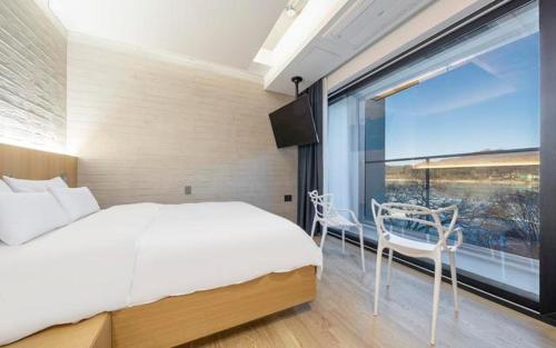 a bedroom with a white bed and a large window at The Line Hotel in Yangpyeong