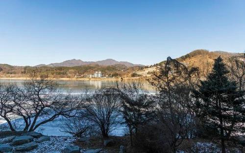 a body of water with trees and mountains in the background at The Line Hotel in Yangpyeong