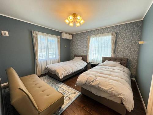 um quarto com 2 camas, uma cadeira e janelas em Queen Anne Style Luxury Vacation Villa em Miyota