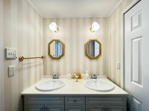 a bathroom with two sinks and two mirrors at Queen Anne Style Luxury Vacation Villa in Miyota