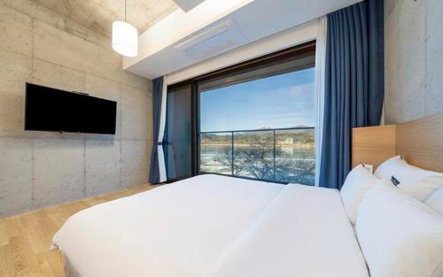 a bedroom with a large white bed and a large window at The Line Hotel in Yangpyeong