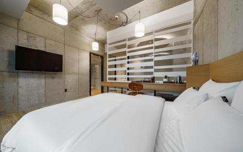 a bedroom with a white bed and a television at The Line Hotel in Yangpyeong