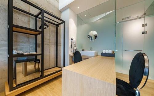 a bathroom with a glass shower with two black chairs at The Line Hotel in Yangpyeong