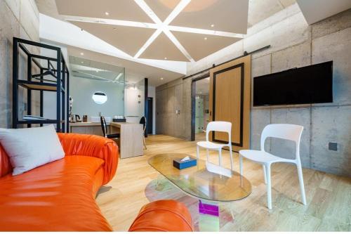 a living room with an orange couch and two white chairs at The Line Hotel in Yangpyeong