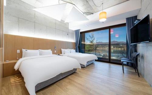 a bedroom with two beds and a flat screen tv at The Line Hotel in Yangpyeong