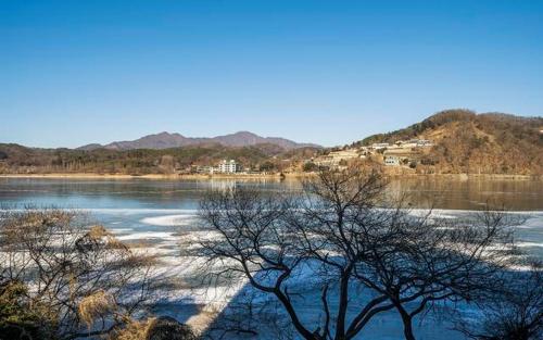 a body of water with trees and mountains in the background at The Line Hotel in Yangpyeong