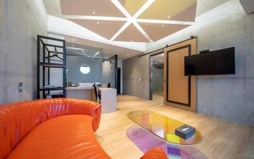 a living room with an orange couch and a glass table at The Line Hotel in Yangpyeong