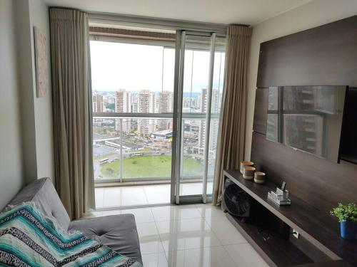 a living room with a large window and a television at Maravilhoso Apartamento em Brasília DF in Brasilia