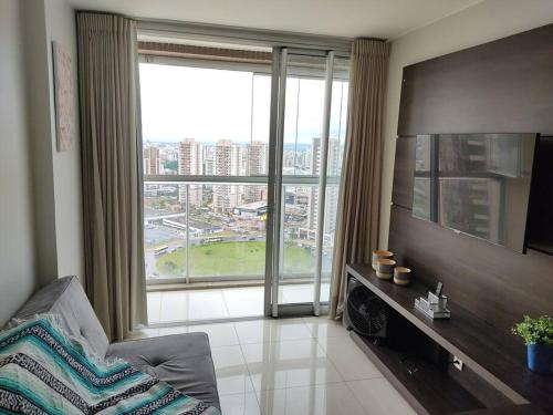 a living room with a large window and a television at Aconchego dentro do Shopping em Brasília in Brasilia