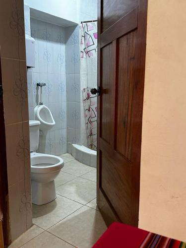 a bathroom with a toilet and a wooden door at Tullpa Rumy Lodge in Yungay