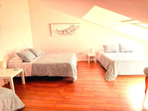 a bedroom with two beds and a wooden floor at TOLETUM low cost LOFTS diáfanos o 2dormitorios PARKING Municipal Gratis al aire libre a 100m in Toledo