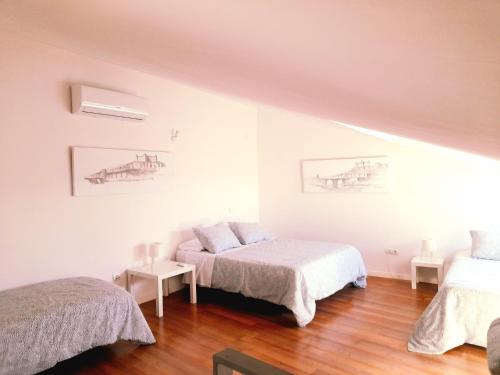 a white room with two beds and wooden floors at TOLETUM low cost LOFTS diáfanos o 2dormitorios PARKING Municipal Gratis al aire libre a 100m in Toledo