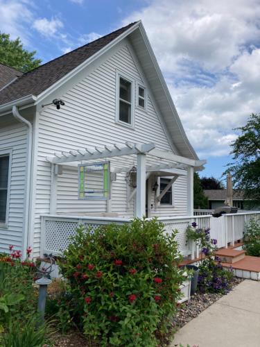 a white house with a porch and a fence at Cozy Algoma Retreat! Minutes to Beach and Downtown! in Algoma