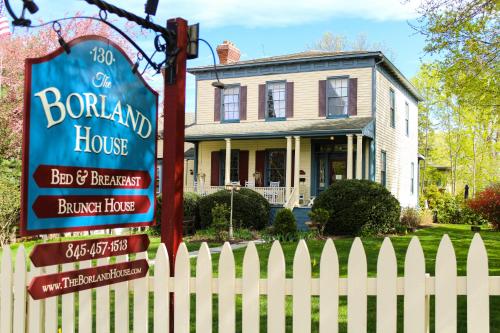 un cartello di fronte a una casa con una recinzione bianca di The Borland House Inn a Montgomery