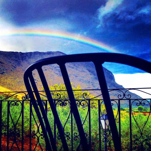 a rainbow in the sky behind a fence with a car at Poggio di mare in Castelluzzo