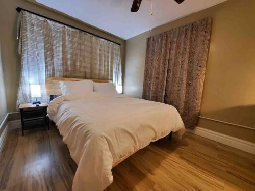 a bedroom with a large white bed and a window at Comfortable getaway Single bedroom full apartment in Niagara Falls