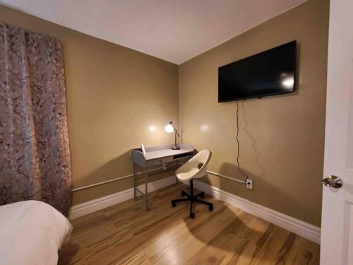 a bedroom with a desk and a television on the wall at Comfortable getaway Single bedroom full apartment in Niagara Falls