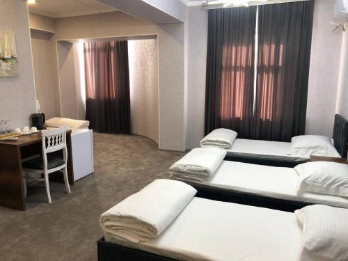 een kamer met 4 bedden, een bureau en een bureau bij Ibn Sino Hotel in Bukhara