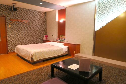 鳥栖市にあるホテル シルクの森（大人専用）のベッドとテーブルが備わるホテルルームです。