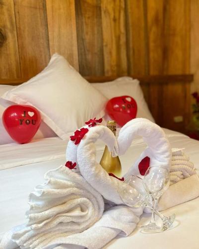a swan towel and a glass of wine on a bed at Guayabo Hostal Mindo in Mindo
