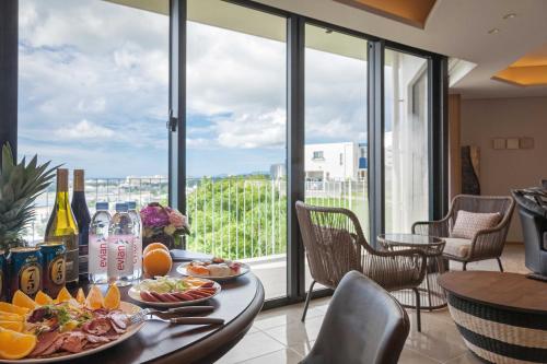 a table with food on it in a room with windows at 恩納オーシャンビュースイート in Nakadomari