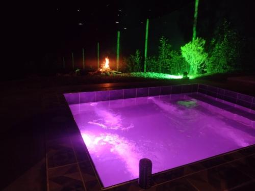una piscina iluminada por la noche con luces moradas en Cabaña Macareo, en Tuluá