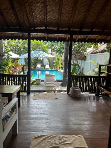 a patio with a pool and a chair and an umbrella at Unzipp Bungalows Gili Air in Gili Islands