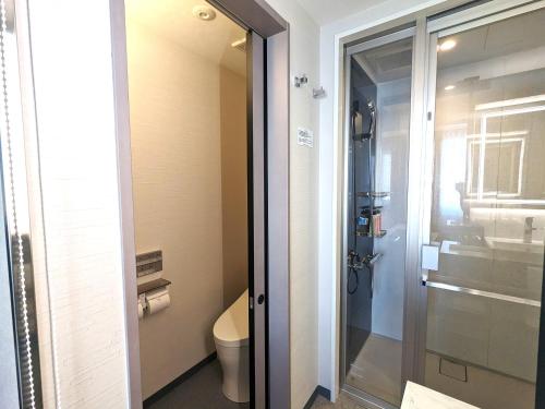 baño con aseo y puerta de ducha de cristal en Green Rich Hotel Tokuyama Ekimae en Shunan