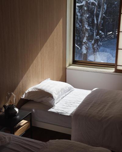a bedroom with two beds and a window with snow at HAKUBA76 in Hakuba