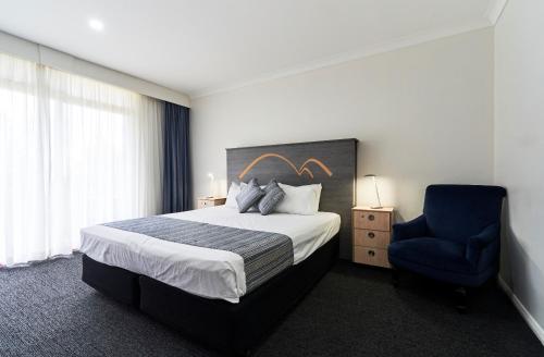 a hotel room with a bed and a blue chair at Leura Gardens Resort in Leura