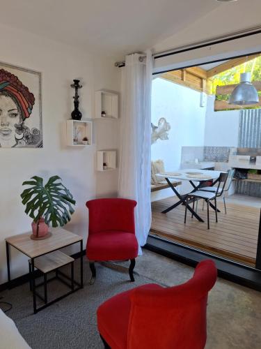 Una sala de estar con una silla roja y una mesa. en Yaka, en Saint-Paul