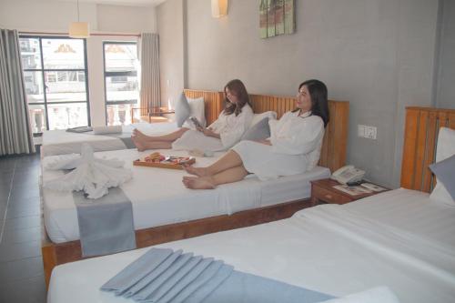 Grand Elevation Hotel في بنوم بنه: وجود سيدتان جالستان على الأسرة في غرفة في الفندق