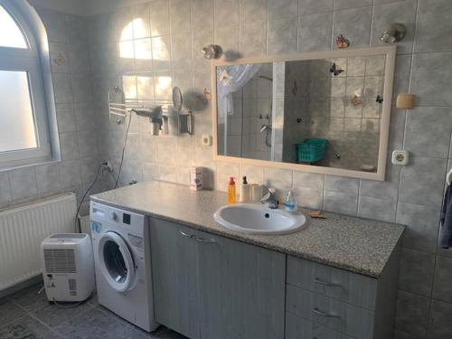 a bathroom with a sink and a washing machine at Érd - Csendes, kényelmes családi ház in Érd