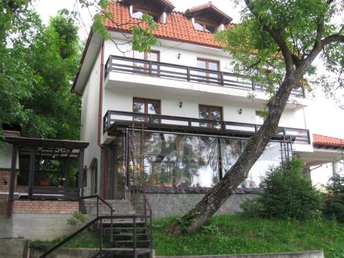 a white house with a tree in front of it at Pensiunea Comarnic-Moisa in Comarnic