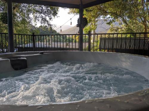 a hot tub filled with water in front of a fence at Littlehurst Lodge in Millgrove
