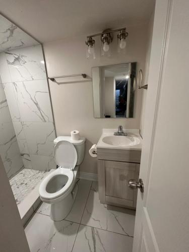 a white bathroom with a toilet and a sink at C&M Beautiful Basement in Brampton