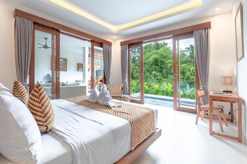 a bedroom with a bed and a view of a pool at Jenar Ubud Villa in Ubud