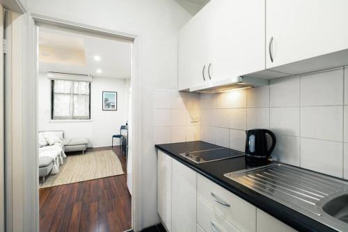 a kitchen with a sink and a living room at Cute & Cosy - Walk to City, Harbour and Museum in Sydney