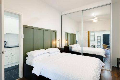 a bedroom with two beds and a large mirror at Cute & Cosy - Walk to City, Harbour and Museum in Sydney