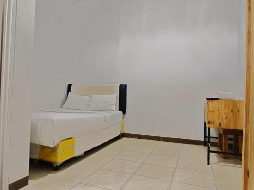 - un petit lit dans une chambre dotée d'un mur blanc dans l'établissement oemah jawa guesthouse jember, à Jember