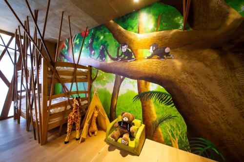 a room with a mural of a tree and stuffed animals at リゾートホテル美萩 in Hagi