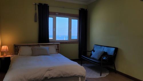 a bedroom with a bed and a chair and a window at Haumok52 Udo in Jeju