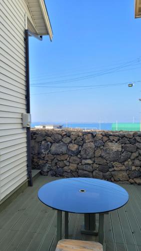 a blue table on a patio with a stone wall at Haumok52 Udo in Jeju