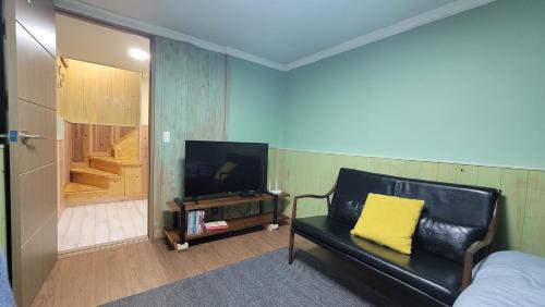 a living room with a couch and a television and a stairway at Haumok52 Udo in Jeju