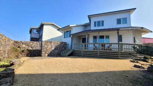 a large white house with a stone retaining wall at Haumok52 Udo in Jeju