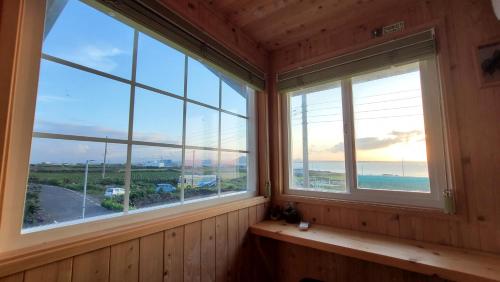 a room with two windows with a view of the ocean at Haumok52 Udo in Jeju