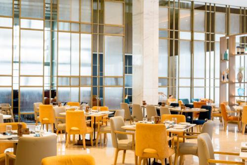 a restaurant with tables and chairs and windows at Holiday Inn Lucknow Airport by IHG in Lucknow
