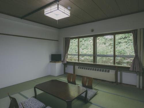 a room with a table and chairs and a window at Chalet Shiga in Yamanouchi