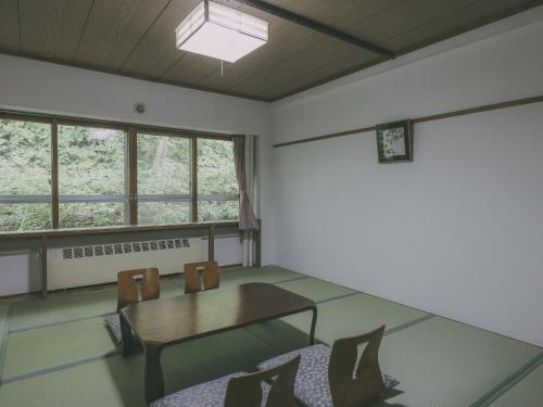 a room with a table and chairs and windows at Chalet Shiga in Yamanouchi
